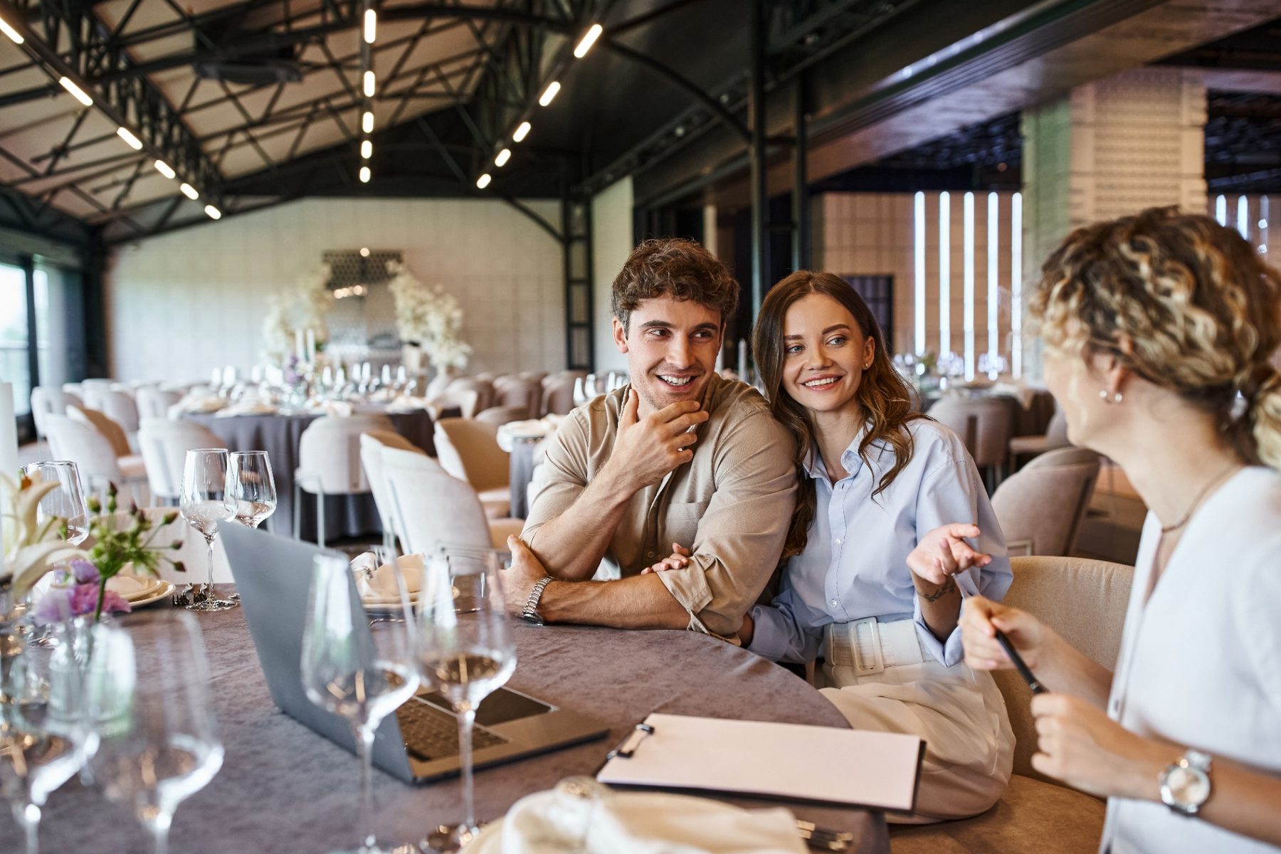 Engaged couple meeting with a venue event manager at a set banquet table