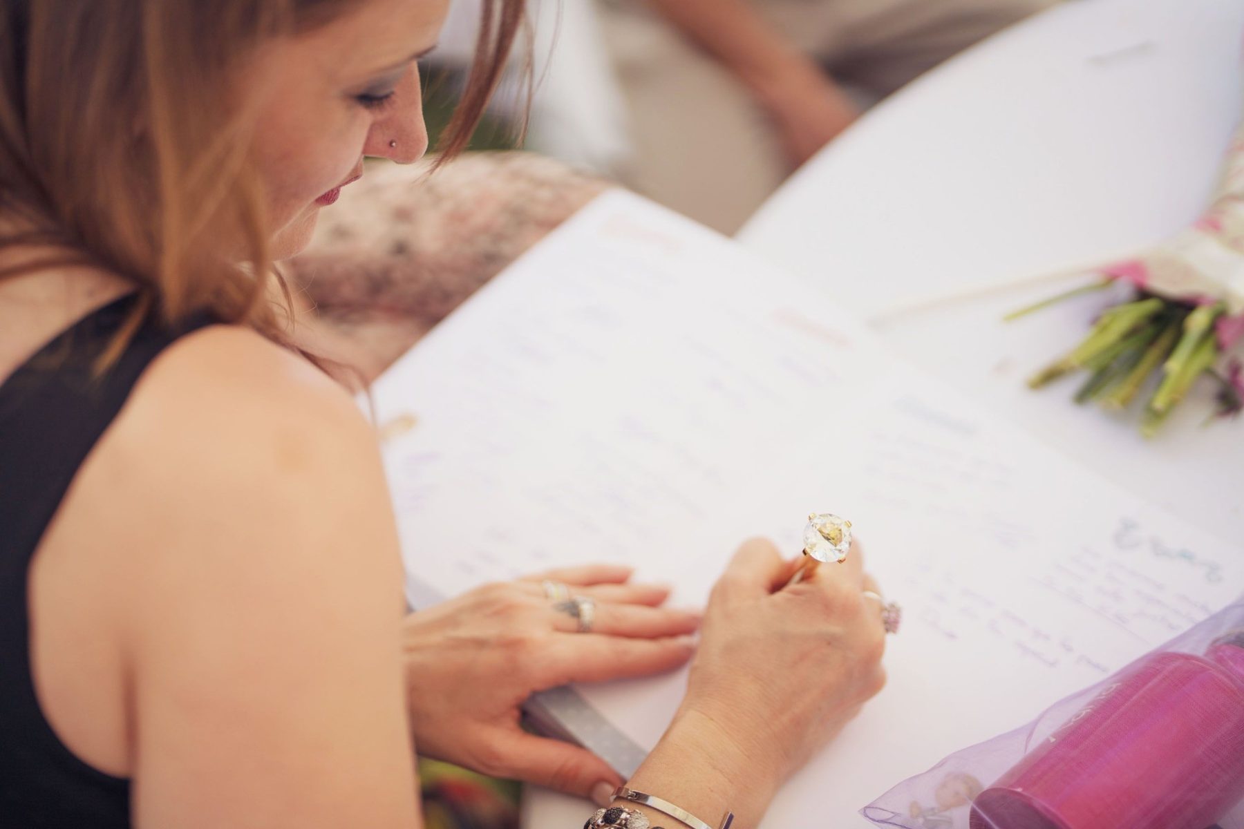 Wedding guest signing an heirloom guestbook at an estate reception