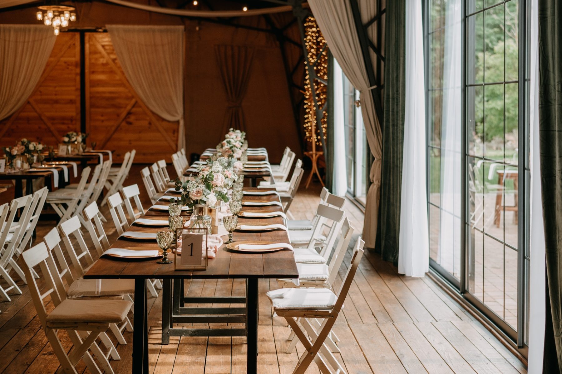 Long wooden reception table with blush florals in a timber-and-glass event space